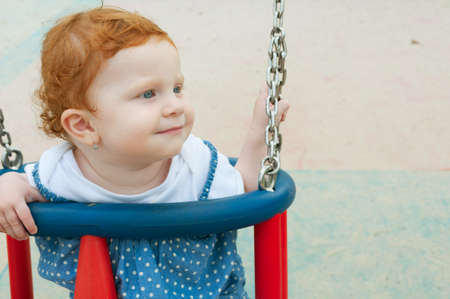 Happy Baby Girl Sitting in the Swingの写真素材