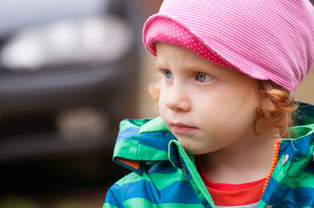 Portrait of thoughtful little girl with car in backgroundの写真素材
