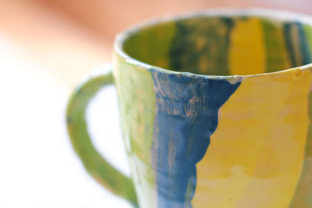 Ceramic handmade cup in yellow green and blue colorの写真素材