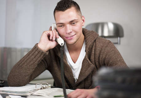 Smiling young businessman having conversation on landline phone. Horizontal shotの写真素材