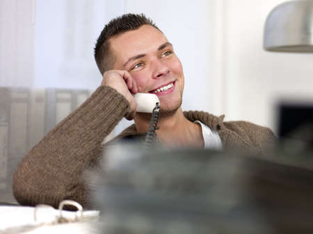 Smiling young businessman having conversation on landline phone. Horizontal shotの写真素材