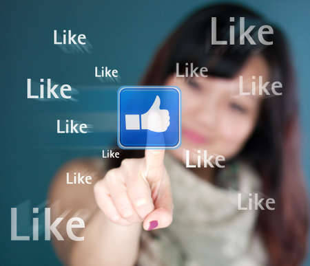 Cute young woman is touching the like buttonの写真素材