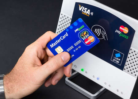 Aachen, Germany - August 05, 2012: Studioshot of payment action with the mastercard paypass credit card in front of a NFC terminal wich accepts visa, mastercard, american express and girogo contactless payments.のeditorial素材