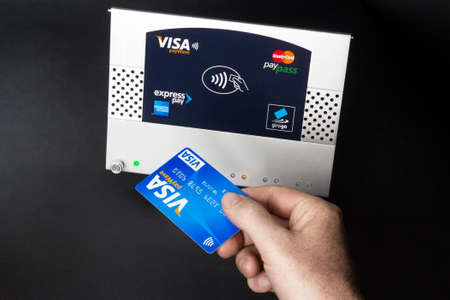 Aachen, Germany - August 05, 2012: Studioshot of payment action with the Visa paywave credit card in front of a NFC terminal wich accepts visa, mastercard, american express and girogo contactless payments.のeditorial素材