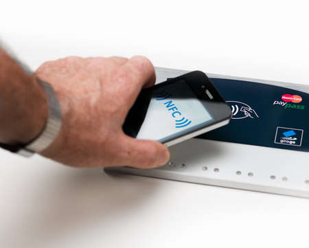 Aachen, Germany - August 10, 2012- Studioshot of payment action with the Apple iPhone 4 in front of a NFC terminal wich accepts visa, mastercard, american express and girogo contactless payments.のeditorial素材