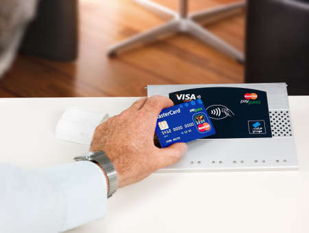 Aachen, Germany - August 11, 2012- Studioshot of payment action with the mastercard paypass credit card in front of a NFC terminal wich accepts visa, mastercard, american express and girogo contactless payments.のeditorial素材