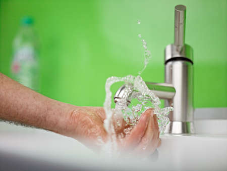 holding hand under sparkling fresh water out of the faucetの写真素材