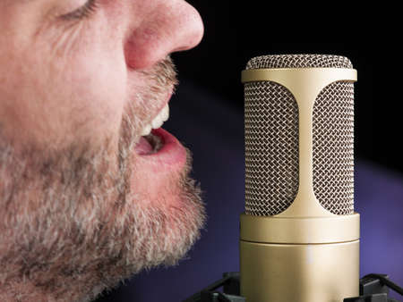 golden broadcast voice microphone on dark background - closeup shotの写真素材