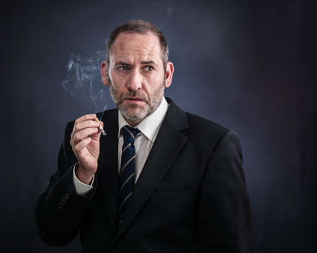 Mature businessman smoking a cigaretteの写真素材