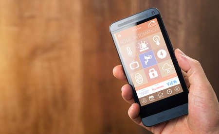 smarthouse home automation device with app icons. Man uses his smartphone with smart home security app to unlock the door of his house.の写真素材