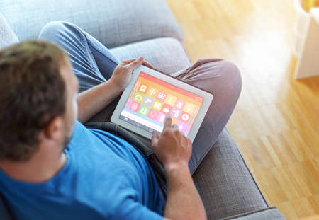 smarthouse home automation device with app icons. Man uses his tablet PC with smart home app to control his house. The New Generation of the Internet of Things.の写真素材