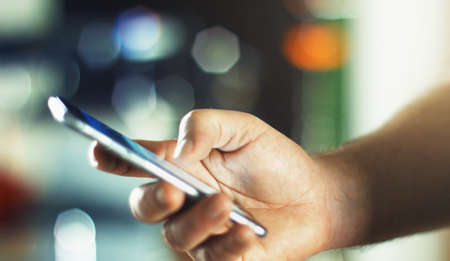 Business Man using mobile phone smart phone in the office. Typing, reading, scrolling the touchscreen - blurry background with space for text.の写真素材