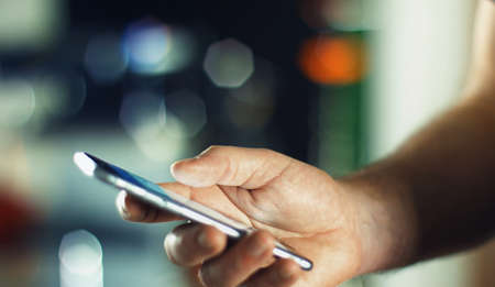 Business Man using mobile phone smart phone in the office. Typing, reading, scrolling the touchscreen - blurry background with space for text.の写真素材