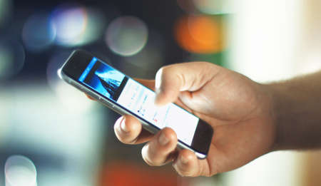 Aachen, Germany, September 28, 2015: close up shot of a young man uses facebook app on the new apple iphone 6s in the officeのeditorial素材