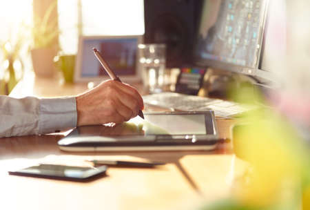 Graphic Designer working with interactive pen display, digital Drawing tablet and Pen on a computer. Smooth tracking shot with nice backlit lensflare.