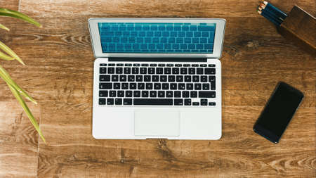 Laptop on Vintage Wooden desktop in modern office with accessoires - top view on desk from aboveの写真素材
