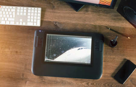 Graphic Designer working with interactive pen display, digital Drawing tablet and Pen on a computer on a wooden desktop. Above view shotの写真素材