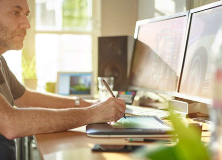 Graphic Designer working with interactive pen display, digital Drawing tablet and Pen on a computer. Smooth tracking shot with nice backlit lensflare.の写真素材