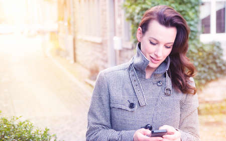 Businesswoman use her mobile phone outdoor in a historic villageの写真素材