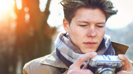 Attractive Tourist taking a photograph with vintage camera of Historic old village / town at sunsetの写真素材