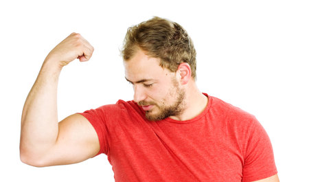 Young man showing his muscles and smiles, success of daily training.