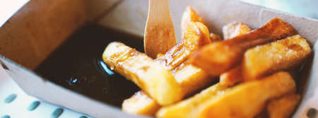 French fries on tracing paper on board on wooden tableの写真素材
