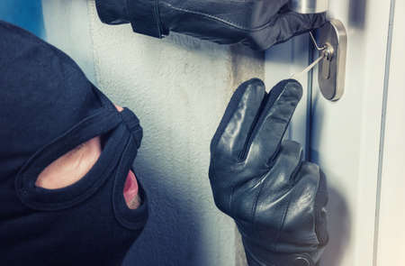masked burglar with crowbar breaking and entering into a victim's homeの写真素材