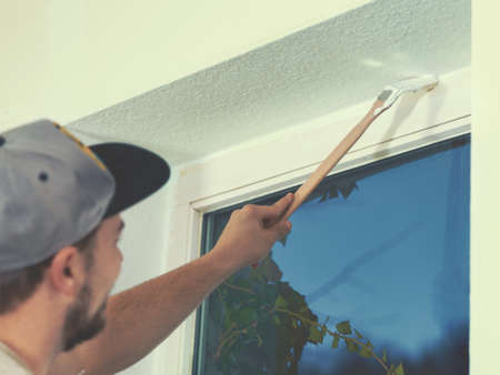 Close up of painter working with paint roller and brushes to paint the room in white colors. dig - do it yourselfの写真素材