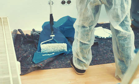 Close up of painter working with paint roller and brushes to paint the room in white colors. dig - do it yourselfの写真素材