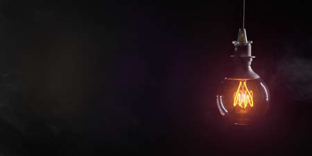 Vintage lightbulb on dark background with bright yellow shining wireの写真素材