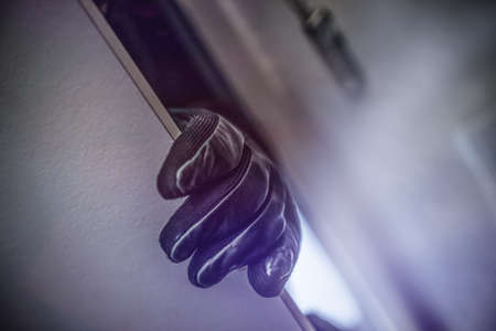 masked burglar with crowbar breaking and entering into a victim's homeの写真素材