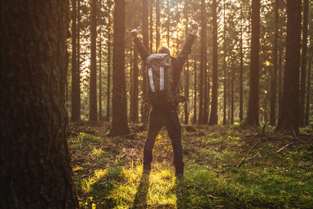Young man stand in forrest and enjoys nature and sunlight