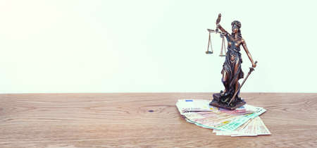 The Statue of Justice - lady justice or Iustitia / Justitia the Roman goddess of Justice on table with money for finance conceptの写真素材