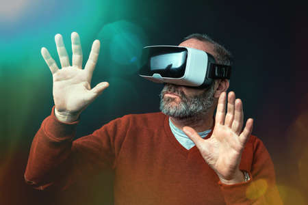 Mature business man wearing virtual reality goggles / VR Glasses to work with in modern officeの写真素材