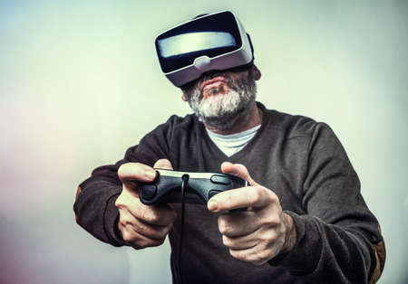 Mature business man wearing virtual reality goggles / VR Glasses to work with in modern officeの写真素材