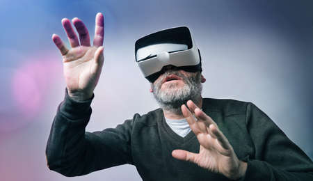 Mature business man wearing virtual reality goggles / VR Glasses to work with in modern officeの写真素材