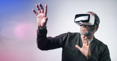 Mature business man wearing virtual reality goggles / VR Glasses to work with in modern officeの写真素材