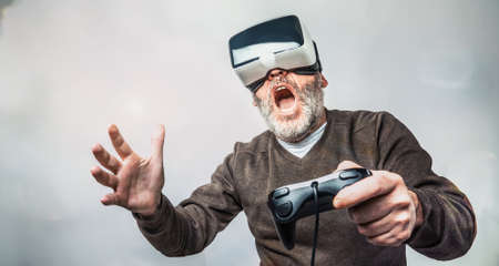 Mature bearded man wearing virtual reality goggles / VR Glasses to play video gamesの写真素材