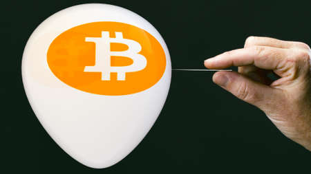 bitcoins concept - bit coin BTC the new virtual money on balloon with needle in hand before burstの写真素材