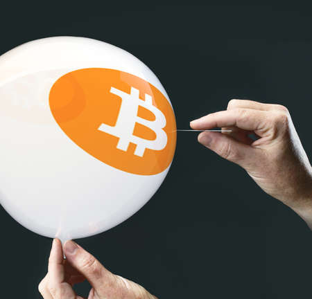 bitcoins concept - bit coin BTC the new virtual money on balloon with needle in hand before burstの写真素材