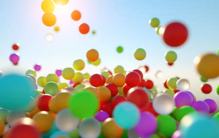 colorful bouncing balls outdoors against blue sunny skyの写真素材