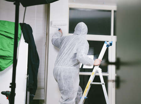 Close up of painter working with paint roller and brushes to paint the room in white colors. dig - do it yourselfの写真素材