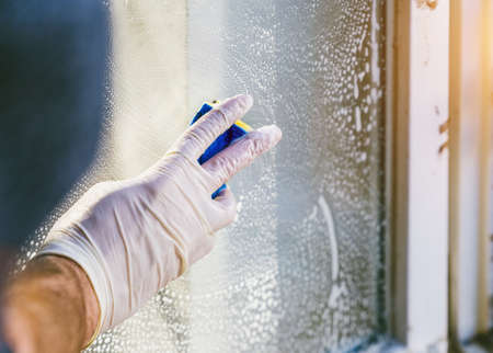young man is using a rag and squeegee while cleaning windows. professional window cleaner.の写真素材