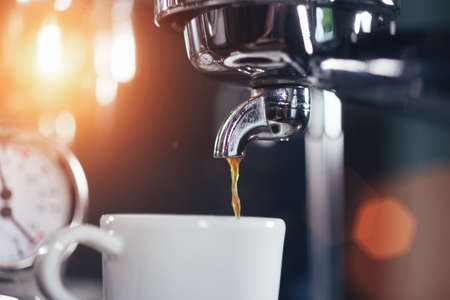 Espresso pouring from classic coffee machine into small white cup. Close-up Shot.の写真素材