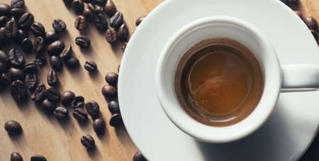 White Coffee Cup filled with Espresso on wooden table with coffee beans. table Top view.の写真素材