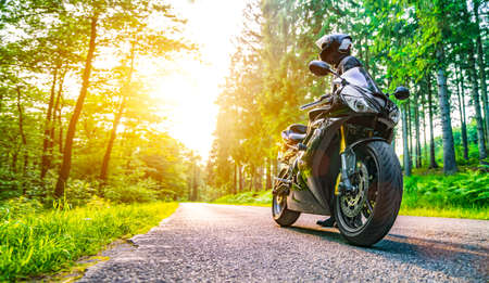 motorbike on the forest road riding. having fun driving the empty road on a motorcycle tour journey. copyspace for your individual text.の写真素材