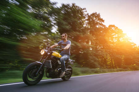 modern scrambler motorbike on the forest road riding. having fun driving the empty road on a motorcycle tour journey. copyspace for your individual text.の写真素材