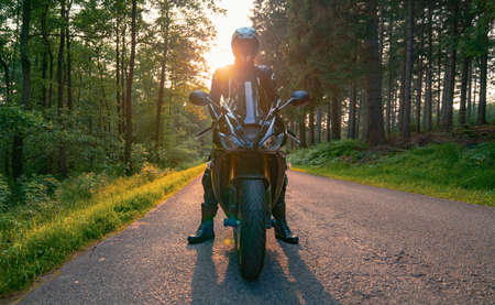 motorbike on the forest road riding. having fun driving the empty road on a motorcycle tour journey. copyspace for your individual text.の写真素材