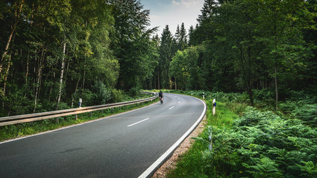 Bike on Long Curvy Forest Road In Alpine Mountainsの写真素材