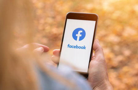AACHEN, GERMANY AUGUST 2019: Woman holding a Apple iPhone opening Facebook app. Facebook is the...